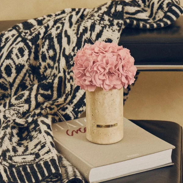 Black chair with beige vase of pink hydrangeas