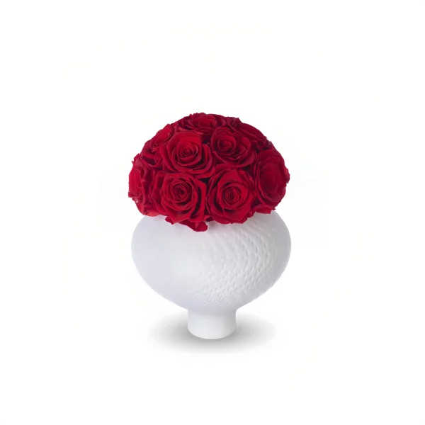 Round textured white vase with ridged pattern topped with spherical bouquet of densely packed deep red roses