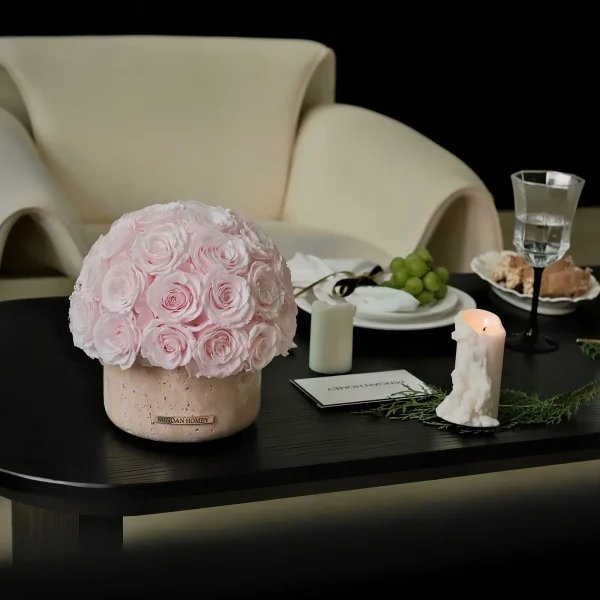 Serene minimalist setting with pink rose floral arrangement in beige vase on black wooden table
