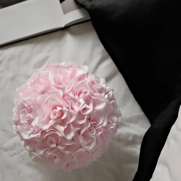Close-up of light pink ruffled flower bouquet on white bed sheet with black fabric