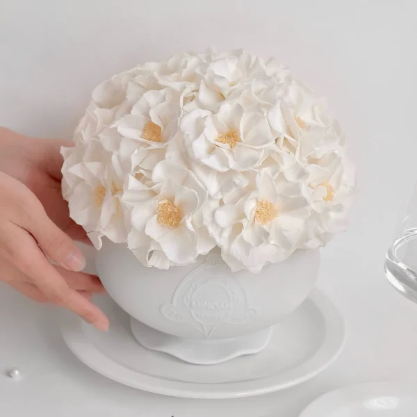 White ceramic bowl with lush white hydrangeas and embossed pattern held by hand